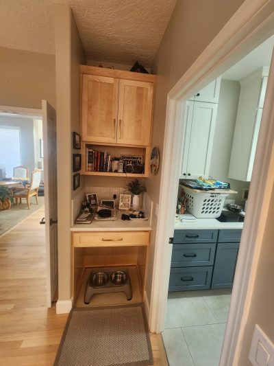Compact kitchen with laundry area: stacked washer/dryer beside light wood cabinetry and blue lower cabinets.