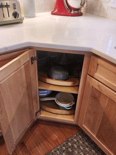 Open wooden kitchen cabinet with dishes and cookware visible on shelves inside; a toaster sits on the counter to the right.
